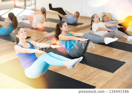 Young woman doing v-sit during warming up in pilates studio Young woman doing v-sit during warming up in pilates studio 138443386