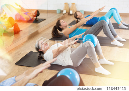 Elderly woman practicing pilates with ball in gym area Elderly woman practicing pilates with ball in gym area 138443413