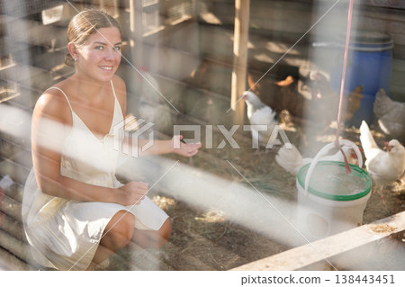 Young woman feeding chickens in henhouse Young woman feeding chickens in henhouse 138443451