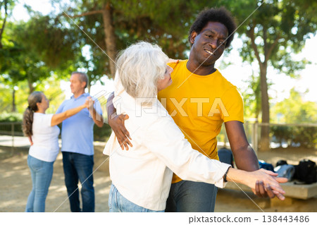 Cheerful multiracial middle aged and older adults enjoying dancing in pairs outdoor at park Cheerful multiracial middle aged and older adults enjoying dancing in pairs outdoor at park 138443486