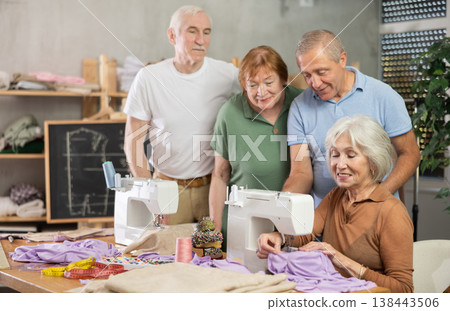 Seamstress explaining sewing techniques to older adults in training workshop Seamstress explaining sewing techniques to older adults in training workshop 138443506