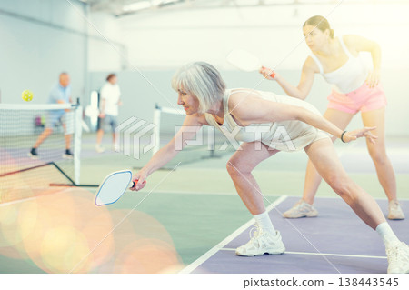 Mature woman playing doubles pickleball game, healthy lifestyle concept Mature woman playing doubles pickleball game, healthy lifestyle concept 138443545