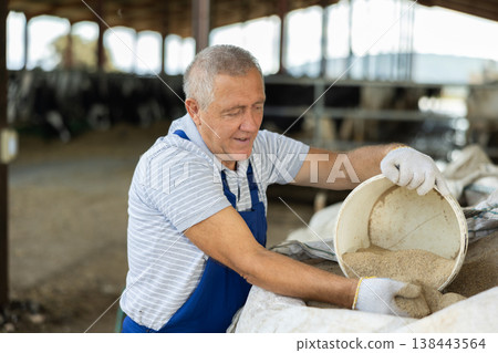Elderly man scooping sand from bag 138443564