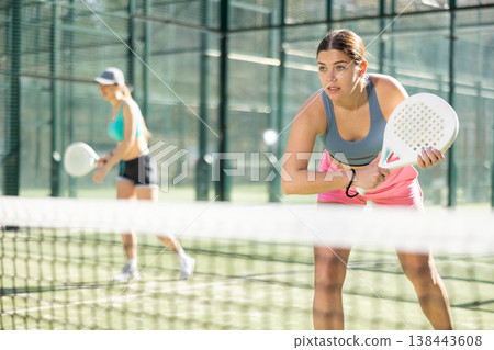 Young woman playing Padel Tennis in open-air tennis court Young woman playing Padel Tennis in open-air tennis court 138443608