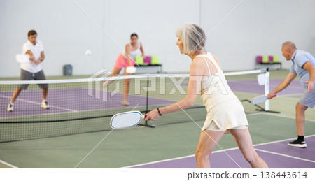 Rear view of sporty senior woman playing pickleball indoors Rear view of sporty senior woman playing pickleball indoors 138443614