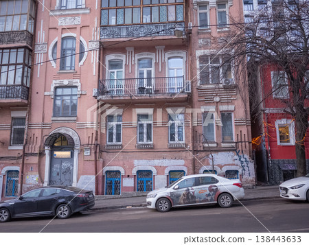 [Ukraine] Exterior view of a historical building in the capital Kyiv and cars parked on the side of a sloping road. 138443633