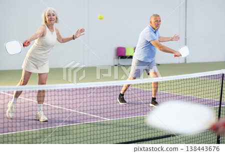 Two pickleball players prepare to return a ball on pickleball court indoor Two pickleball players prepare to return a ball on pickleball court indoor 138443676