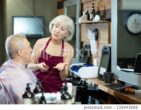 Senior hairdresser woman is discussing haircut with elderly male client. Senior hairdresser woman is discussing haircut with elderly male client. 138443688