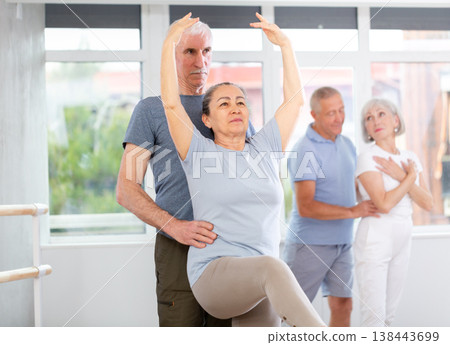 Mature woman practicing ballet positions in pair with man in dance studio 138443699