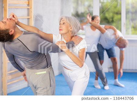 Senior woman in pair with middle-aged coach train Krav Maga and self-defense skills. 138443706