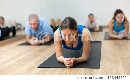 Middle-aged woman practicing pilates on mat in gym area Middle-aged woman practicing pilates on mat in gym area 138443721