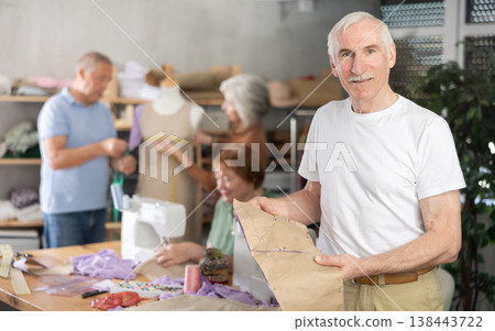 Elderly male participant present fabric billet, other people learn craft of tailor Elderly male participant present fabric billet, other people learn craft of tailor 138443722