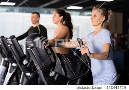 Mature female athlete working out at elliptical machine in gym Mature female athlete working out at elliptical machine in gym 138443729