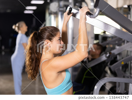 Sporty young woman using shoulder press machine in gym Sporty young woman using shoulder press machine in gym 138443747