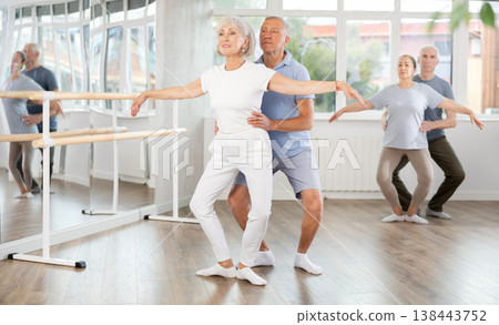 Senior ballet couple partners preparing in rehearsal for contest, training demi plie ballet poses with support in classroom Senior ballet couple partners preparing in rehearsal for contest, training demi plie ballet poses with support in classroom 138443752