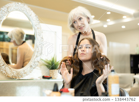 Professional hairdresser is doing fashionable haircut to young woman in hairdress salon Professional hairdresser is doing fashionable haircut to young woman in hairdress salon 138443762