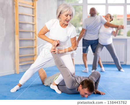 Old woman twisting her opponent's arm during self-defense classes 138443782