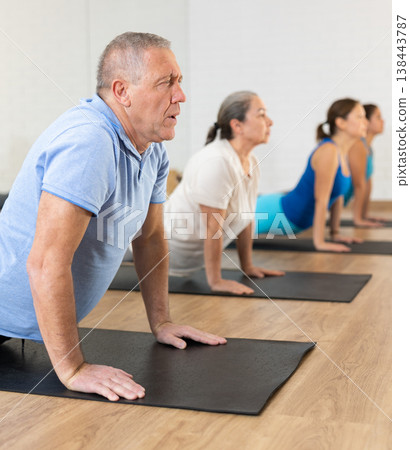 Old man practicing pilates on mat in gym area 138443787