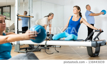 Woman performing pilates exercises on reformer in fitness studio 138443839