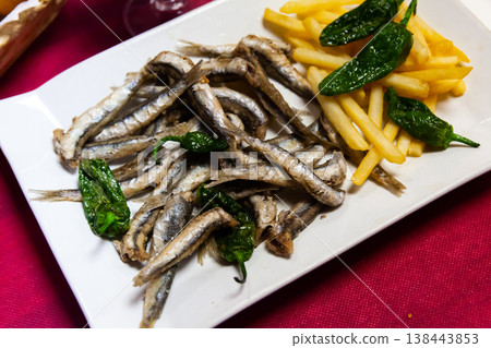 Delicious dish of fried anchovy with french fries and green pepper Delicious dish of fried anchovy with french fries and green pepper 138443853