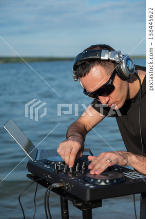 Caucasian man works as a DJ on the beach. Caucasian man works as a DJ on the beach. 138445622