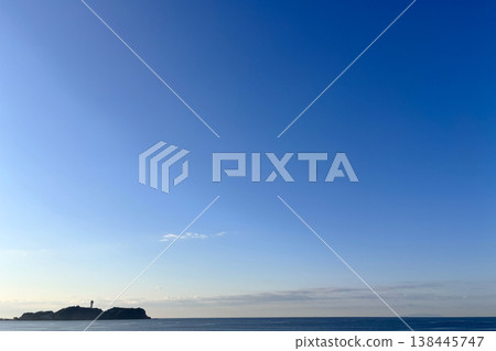 一座燈塔矗立在湛藍的天空和平靜的海面上,宛如一座漂浮的小島。 一座燈塔矗立在湛藍的天空和平靜的海面上,宛如一座漂浮的小島。 138445747