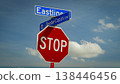Red octagonal stop sign mounted beneath blue street signs at an intersection against a bright blue sky with fluffy clouds, conveying traffic control, safety, direction and urban signage 138446456
