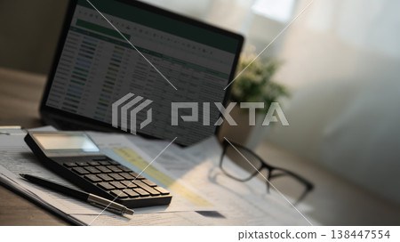 Close-up of a calculator and pen on invoice documents with a laptop displaying a spreadsheet and eyeglasses on a desk, suitable for invoice audit, accounting review, and financial analysis tasks. Close-up of a calculator and pen on invoice documents with a laptop displaying a spreadsheet and eyeglasses on a desk, suitable for invoice audit, accounting review, and financial analysis tasks. 138447554