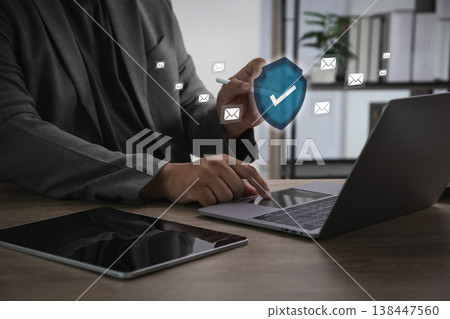 Email compliance management and secure communication concept business working on laptop in office with shield symbolizing regulatory protection and data security. Email compliance management and secure communication concept business working on laptop in office with shield symbolizing regulatory protection and data security. 138447560