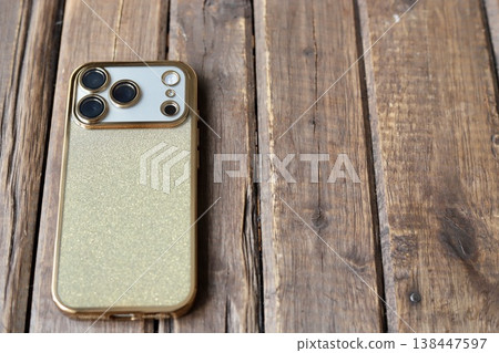 A triple-camera smartphone with a gold glitter back case. 138447597