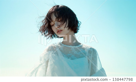A woman in a white dress standing against a blue sky 138447798
