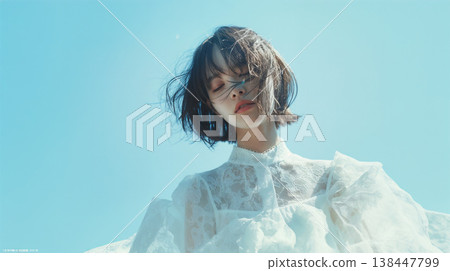 A woman in a white dress standing against a blue sky 138447799