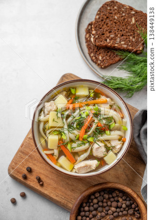 Chicken noodle soup with fresh dill in a bowl on a light textured background Chicken noodle soup with fresh dill in a bowl on a light textured background 138449138