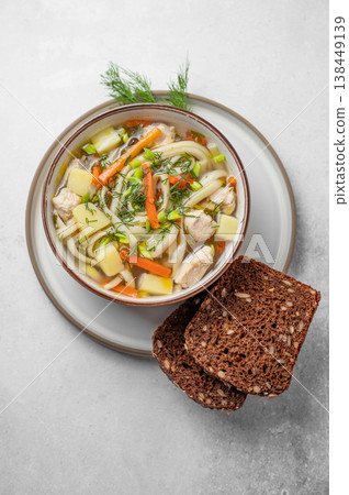 Chicken noodle soup with fresh dill in a bowl on a light textured background Chicken noodle soup with fresh dill in a bowl on a light textured background 138449139