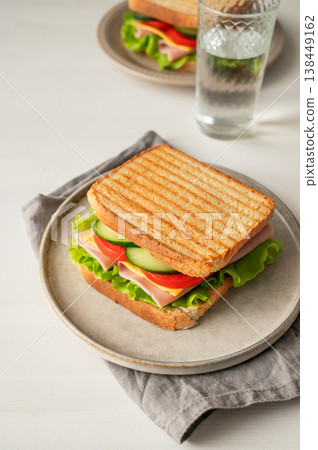 Two club sandwiches with ham, cheese, tomatoes, lettuce, cucumber on a plate on a white background Two club sandwiches with ham, cheese, tomatoes, lettuce, cucumber on a plate on a white background 138449162