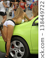 Attractive promo girl in white shorts posing on a lime green car at a car show 138449722