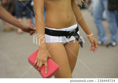 promo girl in white shorts holding a pink sponge, man hand trying to touch her, closeup promo girl in white shorts holding a pink sponge, man hand trying to touch her, closeup 138449724