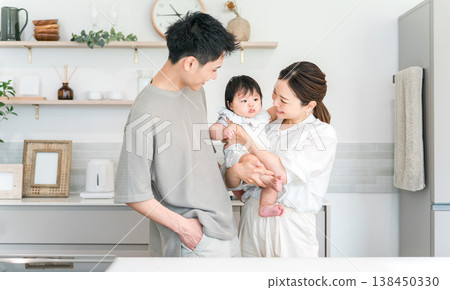 A couple and family holding their baby in the kitchen. A couple and family holding their baby in the kitchen. 138450330