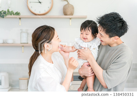 A couple and family holding their baby in the kitchen. A couple and family holding their baby in the kitchen. 138450331