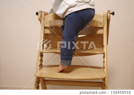 The feet and back view of a toddler climbing onto a high chair by themselves. The feet and back view of a toddler climbing onto a high chair by themselves. 138450558
