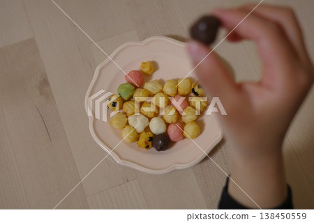 一隻手從盤子裡拿起一根雛飯。 一隻手從盤子裡拿起一根雛飯。 138450559