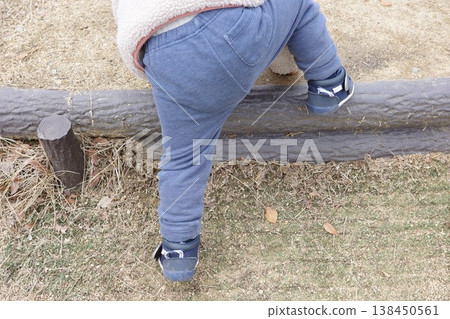 The back view of a child trying to climb over a wooden step. The back view of a child trying to climb over a wooden step. 138450561