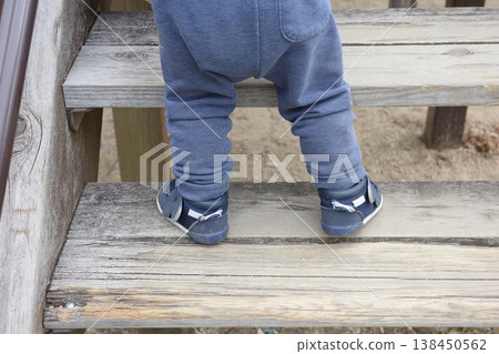 The feet of a child climbing the wooden stairs of the playground equipment in the park The feet of a child climbing the wooden stairs of the playground equipment in the park 138450562