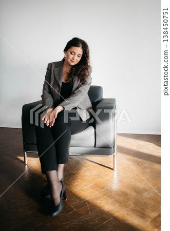 Beautiful green-eyed brunette posing smiling. The woman is dressed in an office style. Portrait of a Happy Woman.  138450751