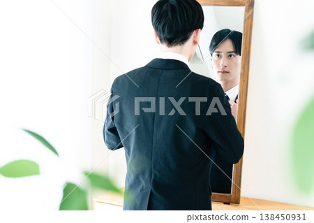 一名身穿西裝的男子在鏡子前整理儀容。 138450931