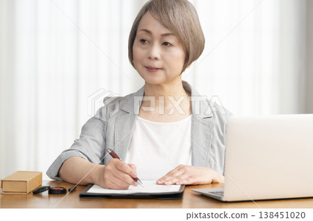 一位老年婦女簽署並蓋章了一份合約。 一位老年婦女簽署並蓋章了一份合約。 138451020