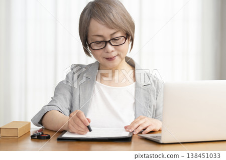 一位老年婦女簽署並蓋章了一份合約。 一位老年婦女簽署並蓋章了一份合約。 138451033