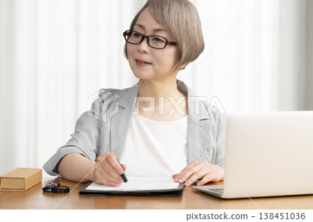 A senior woman signs and seals a contract. 138451036
