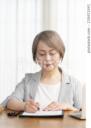 一位老年婦女簽署並蓋章了一份合約。 一位老年婦女簽署並蓋章了一份合約。 138451041