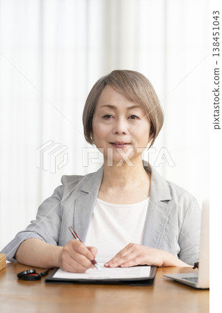 一位老年婦女簽署並蓋章了一份合約。 一位老年婦女簽署並蓋章了一份合約。 138451043